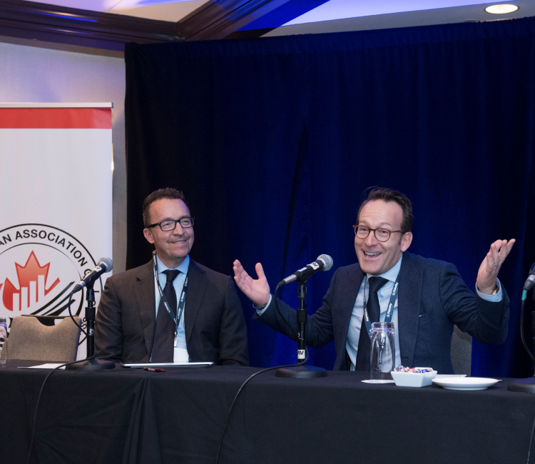 Two seated men speaking at a panel